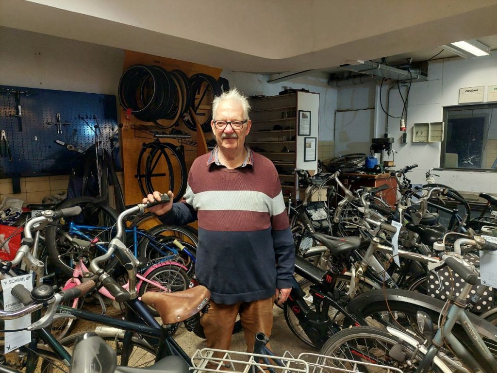 Wim staat vrolijk in zijn fietsenkelder en lacht naar de camera